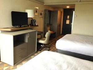Holiday Inn & Suites Pittsfield-Berkshires, an IHG Hotel في بيتسفيلد: غرفة فندقية بسرير ومكتب مع تلفزيون