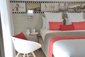een slaapkamer met een bed met rode kussens en een stoel bij Best Western Les Bains Hotel et SPA in Perros-Guirec