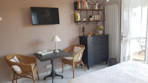 een slaapkamer met een bureau en stoelen en een televisie bij La Parenthèse in Lauris