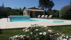 a swimming pool with two lounge chairs and some flowers at La Parenthèse in Lauris