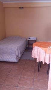 a bedroom with two beds and a table in it at Hotel Don Alfredo in Calama