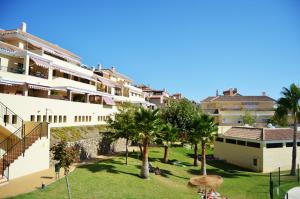 un gran edificio blanco con palmeras en un parque en Terrasol Baviera Golf, en Caleta de Vélez