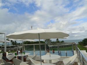 um grande guarda-chuva branco sentado ao lado de uma piscina em Flat Jampa Cobertura Duplex A Beira Mar em João Pessoa