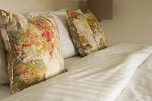 a bed with three pillows on top of it at The Old Schoolhouse Inn in Comber