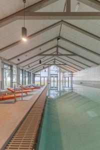 un gran edificio con piscina y bancos en ARBOREA Marina Resort Neustadt, en Neustadt in Holstein