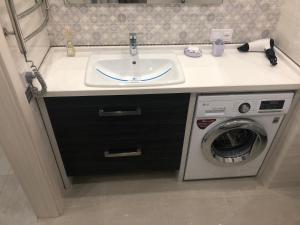 a bathroom with a sink and a washing machine at The Rooms Apart in Odesa