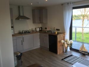 a kitchen with white cabinets and a large window at Lakeside Apartment in Enniskillen