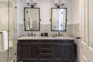 a bathroom with two sinks and two mirrors at Royal Frenchmen Hotel and Bar in New Orleans