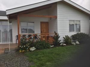 Cette maison blanche dispose d'une terrasse couverte avec une porte en bois. dans l'établissement Cabañas 4 Volcanes Frutillar, à Frutillar