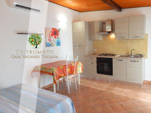 a kitchen with a table and a stove top oven at Case Vacanza Teulada in Teulada