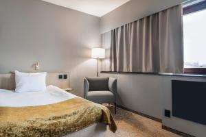una camera d'albergo con letto, sedia e TV di Quality Hotel Royal Corner a Växjö
