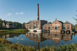 eine alte Fabrik mit Reflexion im Wasser in der Unterkunft De Vooroever in Wervershoof