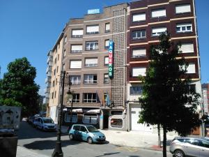 a tall building with cars parked in front of it at Hotel Vaqueros in Langreo