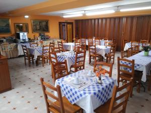 a restaurant with tables and chairs with white and blue tablecloths at Hotel Vaqueros in Langreo