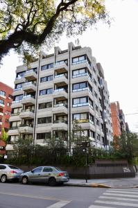 a large apartment building with cars parked in front of it at Golf Tower Suites & Apartments in Buenos Aires