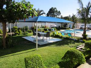 - un parasol bleu dans une cour avec une table et des chaises dans l'établissement Blue Lagoon Lodge Blantyre, à Blantyre