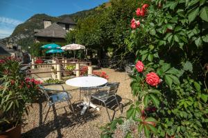 une table et des chaises dans un jardin orné de roses dans l'établissement Hôtel des Voyageurs, à Urdos