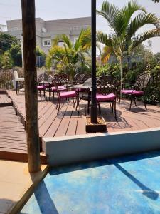 a wooden deck with tables and chairs next to a pool at Orquidea GuestHouse Spa & Restaurant in Maputo