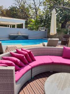 um sofá com almofadas cor-de-rosa sentado ao lado de uma piscina em Orquidea GuestHouse Spa & Restaurant em Maputo