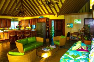 a living room with a green couch and a kitchen at BORA - Fare Matira in Bora Bora