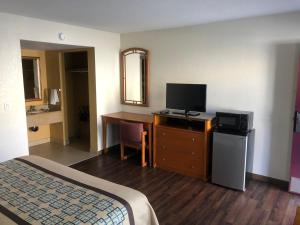 a hotel room with a bed and a desk with a television at Northgate Motel in El Cajon