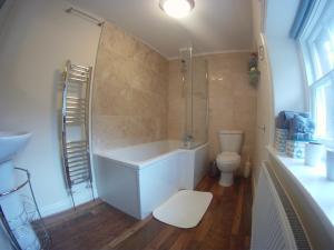 a bathroom with a bath tub and a toilet at Gamekeepers Cottage in Hayfield