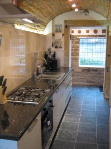 a kitchen with a stove and a counter top at Gamekeepers Cottage in Hayfield