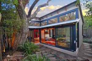 a house with large windows and a tree at Bamboo Cottage in Johannesburg
