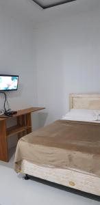 a bedroom with a bed and a desk with a television at Vila tenjo gunung in Cilowa