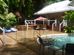 a swimming pool with a deck and a house at Palm Cove Tropic Apartments in Palm Cove
