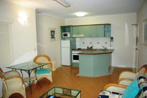 a kitchen with a table, chairs and a refrigerator at Palm Cove Tropic Apartments in Palm Cove