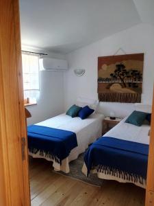 een slaapkamer met 2 bedden met blauwe lakens bij REFÚGIO DO RAPOSO/CASA VEGA in Montes da Senhora