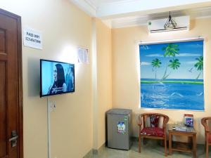 Pokój z telewizorem na ścianie ze stołem i krzesłem w obiekcie Nhat Mai Hotel w mieście Cát Bà