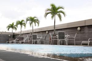 een groep stoelen en palmbomen naast een zwembad bij Imperial Palace Hotel in Miri