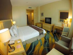 um quarto de hotel com uma cama e uma televisão em Imperial Palace Hotel em Miri