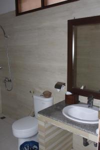 a bathroom with a toilet and a sink and a mirror at Nirwana Buton Villa in Baubau