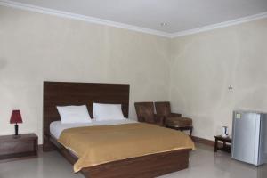 a bedroom with a bed and two chairs and a television at Nirwana Buton Villa in Baubau
