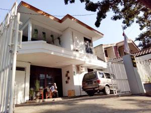 a white house with a car parked in the driveway at RedDoorz near Sanan Malang in Malang