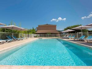 a swimming pool with chairs and umbrellas at Ibis Budget Sisteron in Sisteron