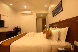 een hotelkamer met een groot wit bed met kussens bij Victory Inn Park Residency in Kunnamkulam