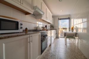 バレンシアにあるLa Seda Stayの白いキャビネット、電子レンジ、テーブル付きのキッチンが備わります。