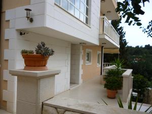 a white building with potted plants on a balcony at Apartments Jani in Hvar