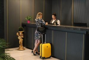 una mujer parada en un mostrador con una maleta amarilla en Nobel Hotel, en Mersin