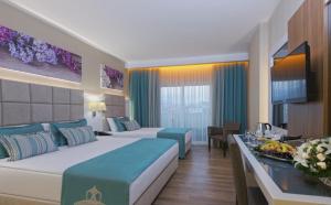 a hotel room with two beds and a television at Asia Beach Resort & Spa Hotel in Alanya