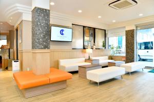 una sala de espera con muebles blancos y TV de pantalla plana. en New Commander Hotel Osaka Neyagawa, en Neyagawa