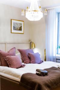 a bedroom with a bed with purple pillows and a chandelier at Hotel Kungsträdgården in Stockholm