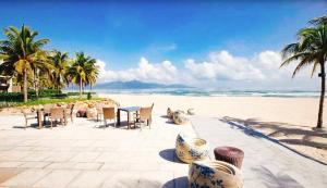 - une table et des chaises sur une plage bordée de palmiers dans l'établissement Mường Thanh Apartment SeaView - Căn Hộ Mường Thanh Đà Nẵng, à Đà Nẵng