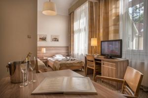 un salon avec une télévision et une table avec un livre dans l'établissement Hotel Cesarskie Ogrody, à Świnoujście