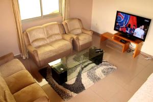 a living room with two couches and a flat screen tv at Princess Endale Residence in Douala