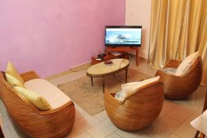 a living room with chairs and a tv and a table at Princess Endale Residence in Douala